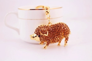 Détail d'un porte-clés cochon en cristal avec strass ambrés sur base en métal doré
