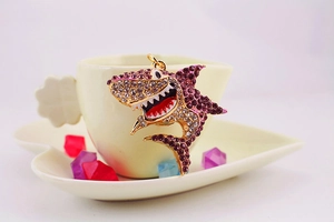 Détail d'un porte-clés requin avec strass violets et émail rouge sur une tasse
