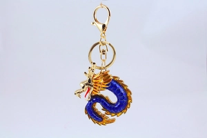 Detalle del llavero de dragón dorado con esmalte azul y cierre de mosquetón grande