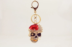 Détail du porte-clés crâne doré en cristal avec strass et décorations en émail rouge