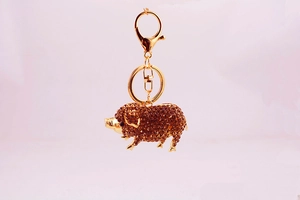 Gros plan du porte-clés cochon doré avec cristaux ambrés et fermoir mousqueton pivotant