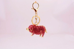 Vue détaillée du porte-clés cochon doré avec strass roses scintillants et fermoir homard