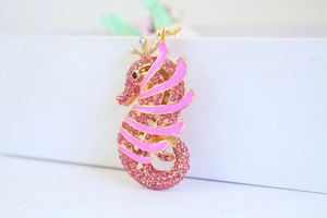 Macro view of pink rhinestone seahorse keychain with gold alloy finish and crown detail