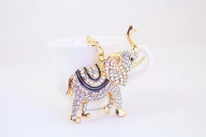 Détail d'un pendentif éléphant doré avec strass posé sur une tasse en céramique blanche