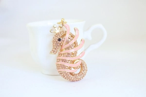 Macro detail of seahorse pendant with pink rhinestones, enamel work and golden finish