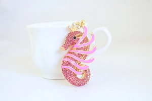 Macro shot of pink rhinestone seahorse keychain with gold alloy crown and enamel details