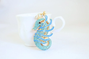 Macro detail of seahorse keychain featuring light blue rhinestones and gold plating