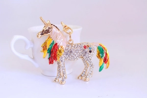Macro detail of a colorful pegasus keychain with white crystals and gold metal finish
