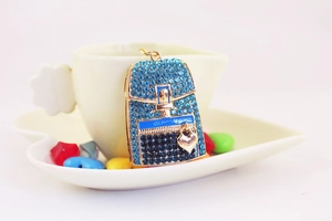 Detail of blue rhinestone backpack pendant with gold heart charm near a ceramic cup