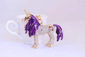 Close-up of golden unicorn keychain with purple enamel mane and sparkling crystals