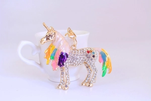 Detail of colorful Pegasus keychain with crystals and rainbow enamel wings on a cup