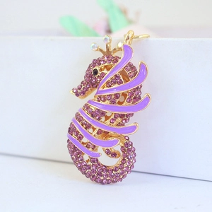 Sparkling seahorse keychain with purple rhinestones and crown detail on white background