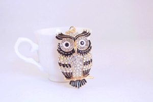 Détail d'un porte-clés hibou doré orné de cristaux brillants suspendu à une tasse blanche