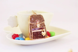 Macro detail of a rhinestone backpack keychain with heart pendant on a coffee cup