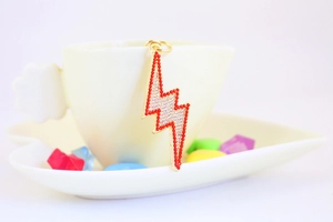 Detail of lightning bolt keychain with red and white rhinestones on a ceramic cup