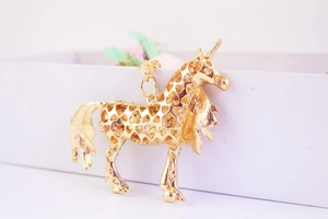 Close-up of golden unicorn pendant featuring hollow heart patterns and metallic finish