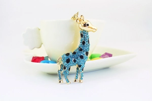 Detailed macro shot of a blue rhinestone-studded giraffe keychain with golden alloy finish