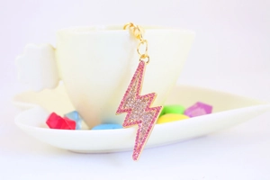 Detail of pink rhinestone lightning bolt keychain charm on a white ceramic coffee cup
