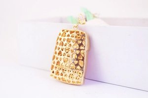 Macro view of gold heart cutout metal pendant with trapezoid shape and ring hook