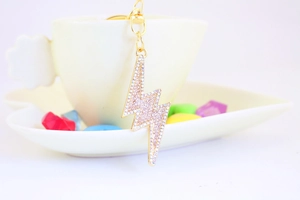 Macro detail of lightning bolt keychain with iridescent AB rhinestones on a gold alloy base