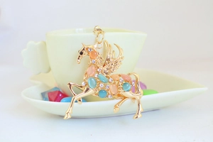 Nahaufnahme des goldenen Pegasus-Anhängers mit Opalen und funkelnden Strasssteinen