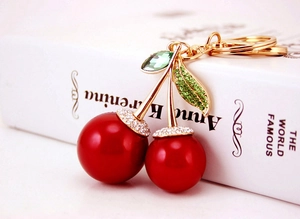 Detail of red cherry keychain featuring green rhinestone leaves and gold lobster clasp