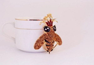 Detalle de un llavero de abeja con diamantes de imitación sobre una taza blanca