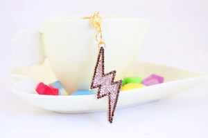 Detail of lightning bolt keychain with black and white rhinestones on gold metal link