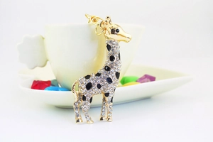 Close-up of golden giraffe keychain featuring sparkling white rhinestones and black enamel dots
