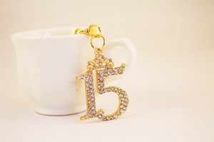 Detail shot of a sparkling gold number 15 keychain with rhinestones and a small crown