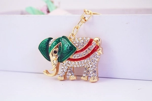 Detail of golden elephant keychain with white rhinestones and green enamel flower patterns