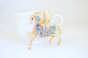 Detailansicht des goldenen Pegasus-Anhängers mit blauen Strasssteinen und Kristallflügeln