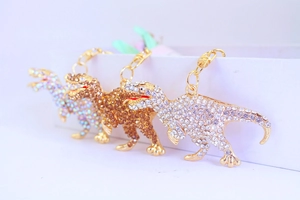 Detailed view of three sparkly rhinestone dinosaur keychains in white and gold colors