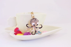Detailed view of octopus keychain with gray rhinestones and black enamel on a cup