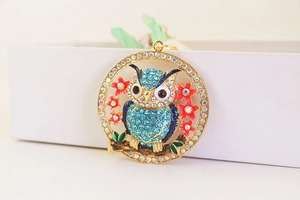 Close-up of owl pendant keychain with blue rhinestones and pink floral details