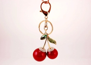 Close-up of sparkling red cherry keychain with green crystal leaves and gold lobster clasp