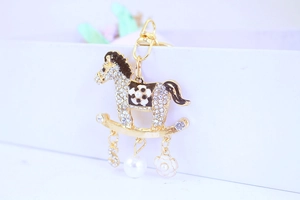 Détail d'un porte-clés carrousel avec émail noir, perle et breloques camélia