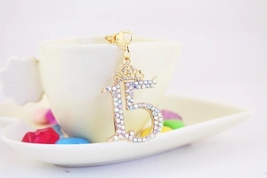 Detail of gold number 15 charm with crown and iridescent rhinestones on a ceramic cup