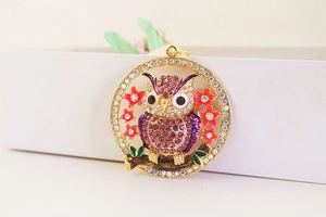 Macro shot of a purple rhinestone owl pendant with gold plating and white crystals