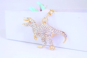 Detail of a sparkling rhinestone dinosaur keychain with golden alloy finish and lobster clasp