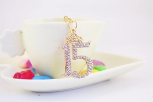 Close-up of gold crown number 15 keychain with sparkling rhinestones on ceramic