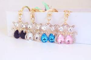 Detailed view of four colorful rhinestone cat keychains on a white display stand