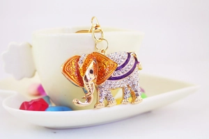 Detail of colorful crystal elephant keychain with orange enamel ears on a coffee cup
