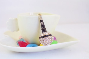Close-up of a sparkling microphone keychain with rhinestones hanging on a coffee cup