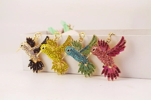 Détail de quatre porte-clés colibri colorés avec strass brillants en diverses finitions