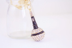 Macro shot of microphone keychain with black enamel and sparkling crystal pavé details