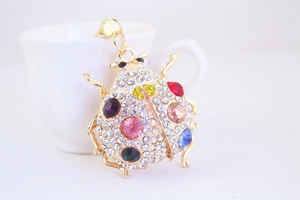 Close-up of golden ladybug keychain with colorful gemstones and sparkling rhinestones