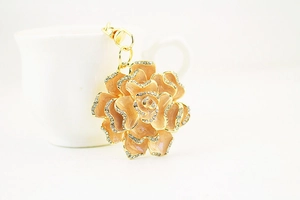 Macro detail of pink enamel rose keychain with white rhinestones and golden metal ring