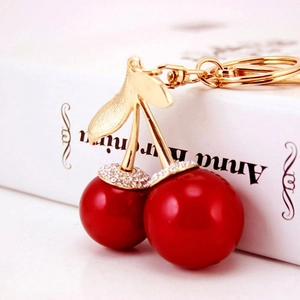 Sparkling rhinestone cherry keychain with red beads and gold metal on a white book
