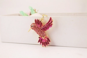 Détail macro du pendentif colibri avec cristaux roses et alliage plaqué or jaune